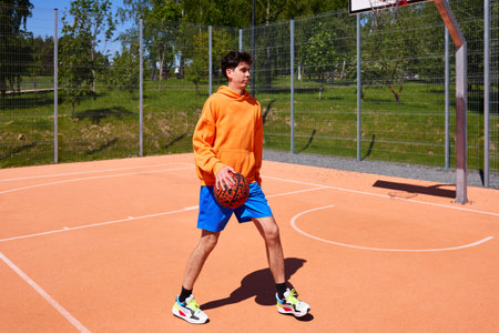 Man training alone on a basketball court outdoors.