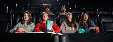 Panoramic photo of friends who are sitting in the cinemaの写真素材