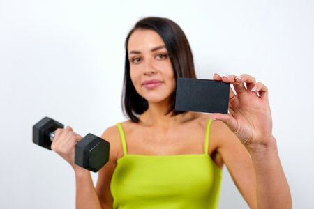 Cute athletic woman in a yellow top holding a gym membership.の写真素材