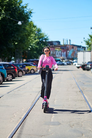 Mobile transport concept, young woman enjoying a ride on an electric scooter.の写真素材