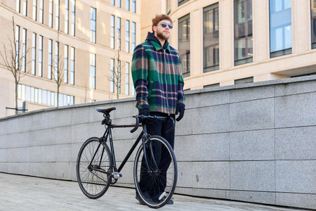 Young brutal man in sunglasses rides a bicycle on a sunny day off.の写真素材