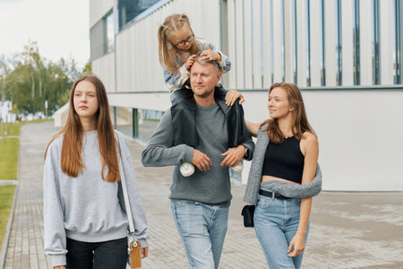 A happy family of mom, dad and two daughters are walking through the city.の写真素材