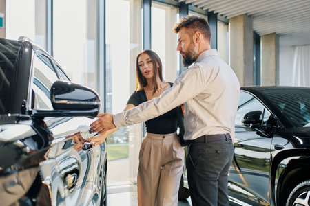 A couple of a man and a woman walk around a car dealership and choose a carの写真素材