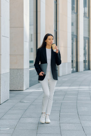 Successful businesswoman in a jacket went out to drink coffee during her lunch break from the office.の写真素材