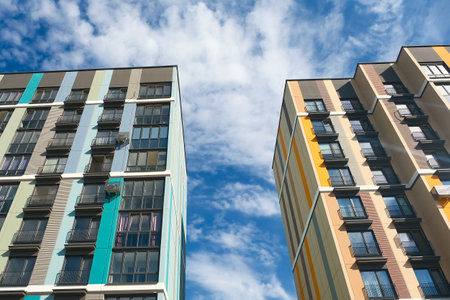 Apartment buildings against a bright blue sky with fluffy cloudsの写真素材