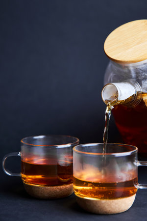 Man pours tea into cups from a teapot.
