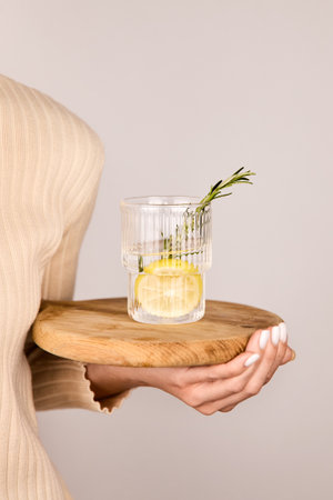 Woman holding glass glass with lemon water and rosemary.の写真素材