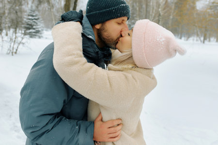 Two people embrace each other in a snowy landscape, sharing a tender kiss.の写真素材