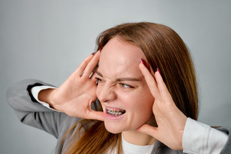 A person grimaces while showing braces on their teeth