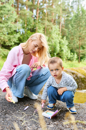 Motherhood concept. Mom and child have fun and draw on the asphalt.の写真素材
