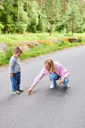 Babysitter and child draw on the asphalt in summer.の写真素材