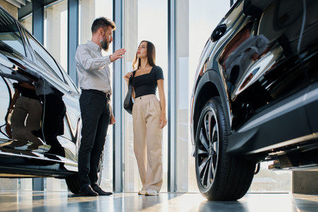 Man and woman talking about a car model in a car dealership.の写真素材