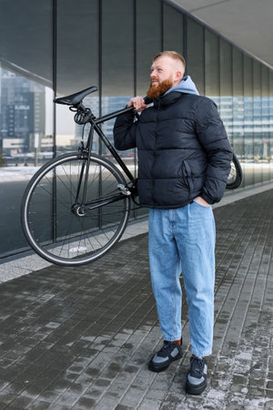 A red-haired man with a beard is holding a bicycle.の写真素材