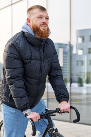 A man with a beard rides a bicycle along the street.の写真素材