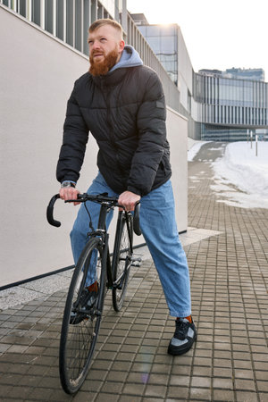 A man in an autumn jacket took a bicycle to get around the city.の写真素材