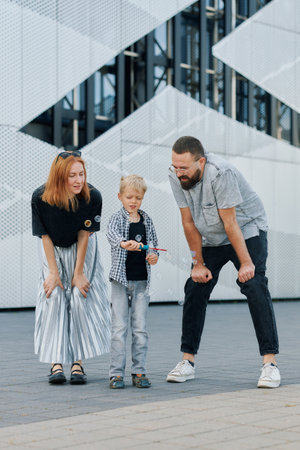 A young boy shows a soap bubbles to his parents, all smiling and enjoying each other's company.