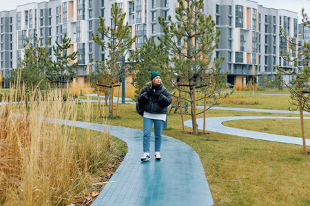 A woman strolls along a blue path surrounded by greenery and contemporary buildings.の写真素材