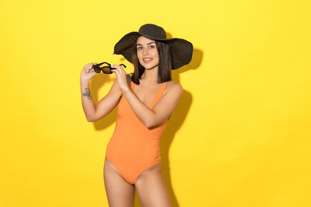 Summer vibes: Woman is staying in her swimsuit and hat. With her sun-proof glasses, she's ready to enjoy a summerの写真素材