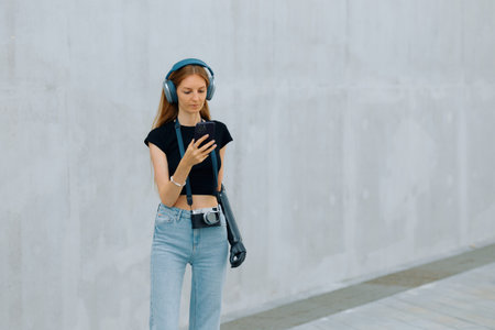 Woman with a bionic arm is walking in a modern setting, using her phone and wearing headphones.