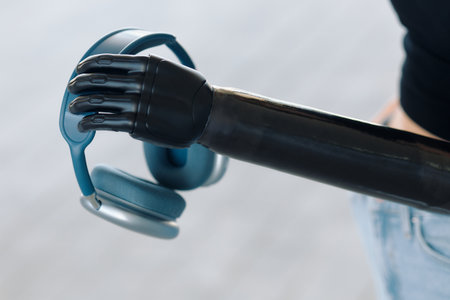 A woman demonstrates her bionic prosthesis by holding a pair of headphonesの写真素材