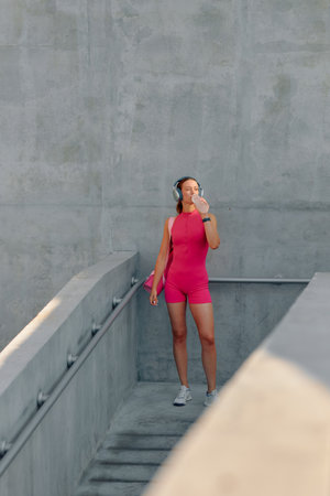 A woman in bright sportswear relaxes outdoors, listening to music in the city.の写真素材