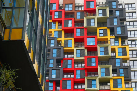 A striking facade showcases a blend of bright colors and geometric shapes on a modern residential building in a bustling city, highlighting innovative design.の写真素材