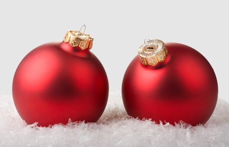 two red christmas balls on snow on grey backgroundの写真素材