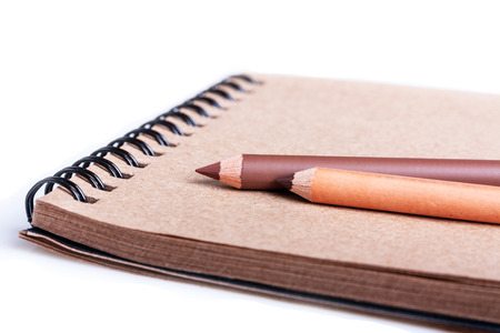 Notebook and two brown pencils isolated on white backgroundの写真素材
