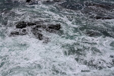 Rolling sea waves slamming on rocksの写真素材