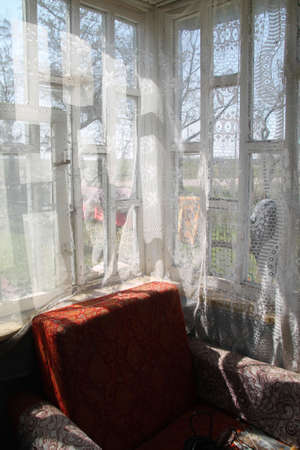 Window with white curtains and a chair in the interior of the houseの写真素材