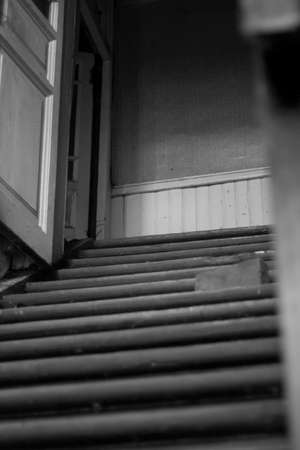 A black and white photo of a staircase leading up to a wooden houseの写真素材