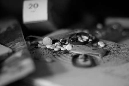 Black and white photo of medicine pills and tablets on a wooden tableの写真素材