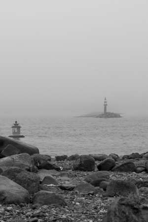 Black and white photo of a lighthouse on a foggy day.の写真素材