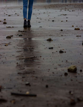 Woman walking on the beach in the rain. Selective focus.の写真素材