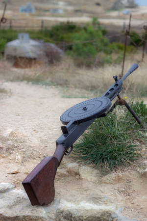 Old machine gun on the ground in the desert. Selective focus.