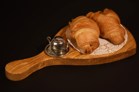 Freshly baked croissants on a wooden board on a black backgroundの写真素材
