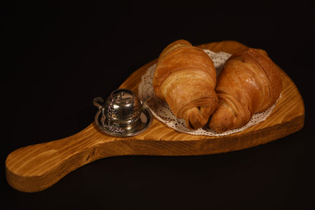 Croissants on a wooden board with a bell on a black backgroundの写真素材