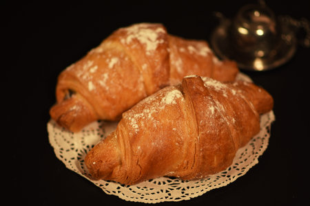 Croissants on a white lace napkin on a black backgroundの写真素材