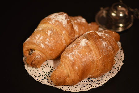 Two croissants on a white lace napkin on a black backgroundの写真素材