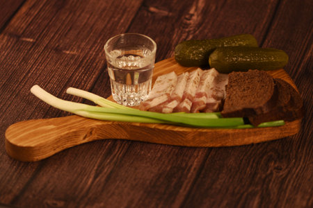 Cold vodka with pickled cucumbers and rye bread on a wooden boardの写真素材