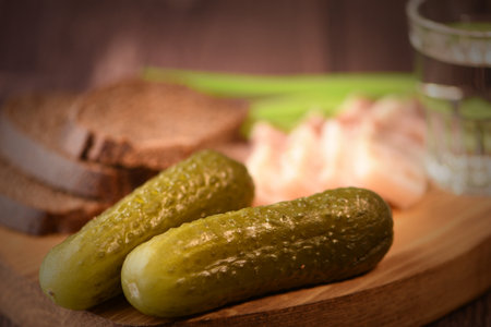Pickled cucumbers with bread and glass of vodka on wooden backgroundの写真素材