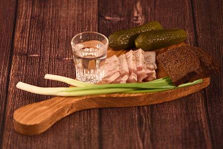 Sandwiches with pickled cucumbers and vodka on a wooden boardの写真素材