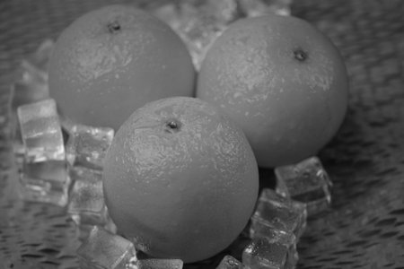 Oranges and ice cubes on a black background. Toned.の写真素材