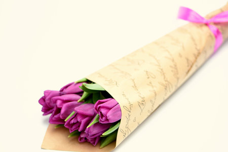 Bouquet of purple tulips wrapped in craft paper on white backgroundの写真素材
