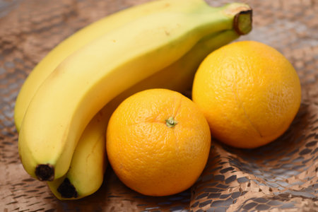 Bananas and oranges on a brown wooden background. close up.の写真素材
