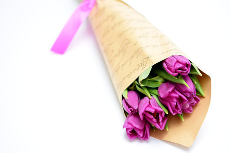 Bouquet of purple tulips on a white background with a pink ribbonの写真素材