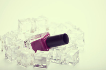 Nail polish and ice cubes on white background. selective focus. Toned.の写真素材