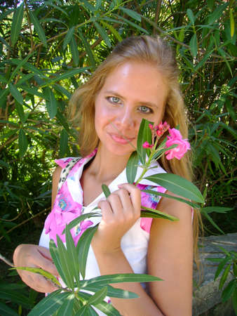 Portrait of a beautiful young with a pink flowerの写真素材