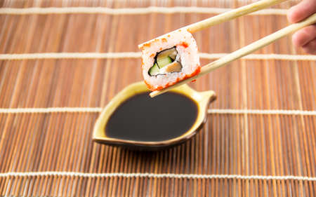 Sushi roll with salmon cucumber and cheese with chopsticks and soy sauce backgroundの写真素材