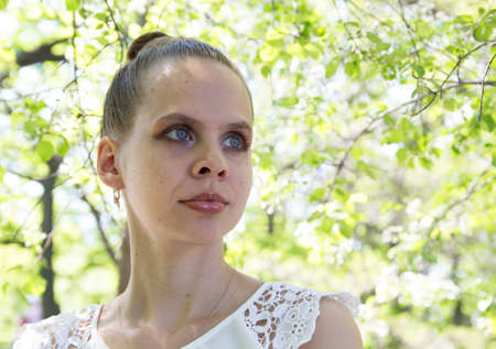 Portrait of a beautiful young girl on a background of flowering treesの写真素材